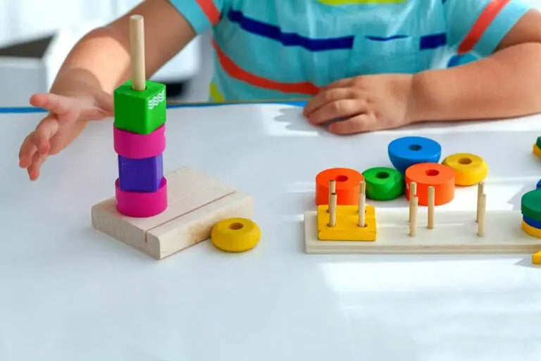 Close-up of a young child threading colorful wooden beads, engaging in a Montessori-inspired activity to develop fine motor skills and promote independent play.